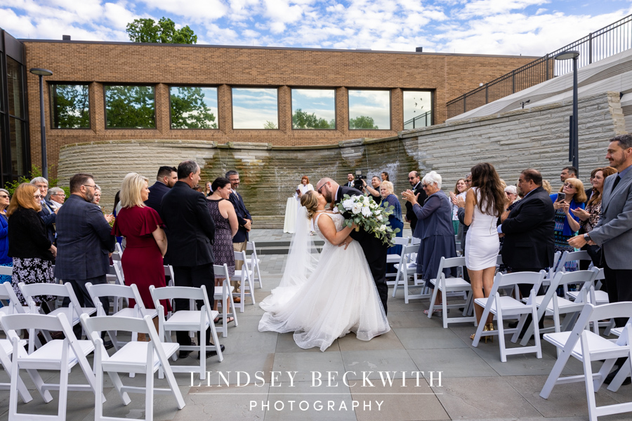 Cleveland Museum of Natural History wedding ceremony bride and groom kiss while guests cheer