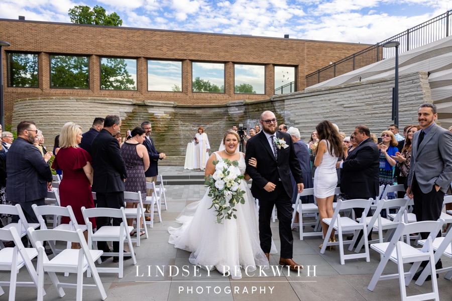 Cleveland Museum of Natural History wedding ceremony bride and groom walk down aisle smiling