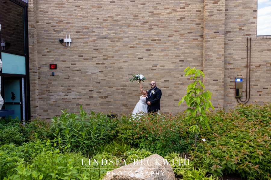 Bride raises bouquet triumphantly after Cleveland Museum of Natural History wedding ceremony
